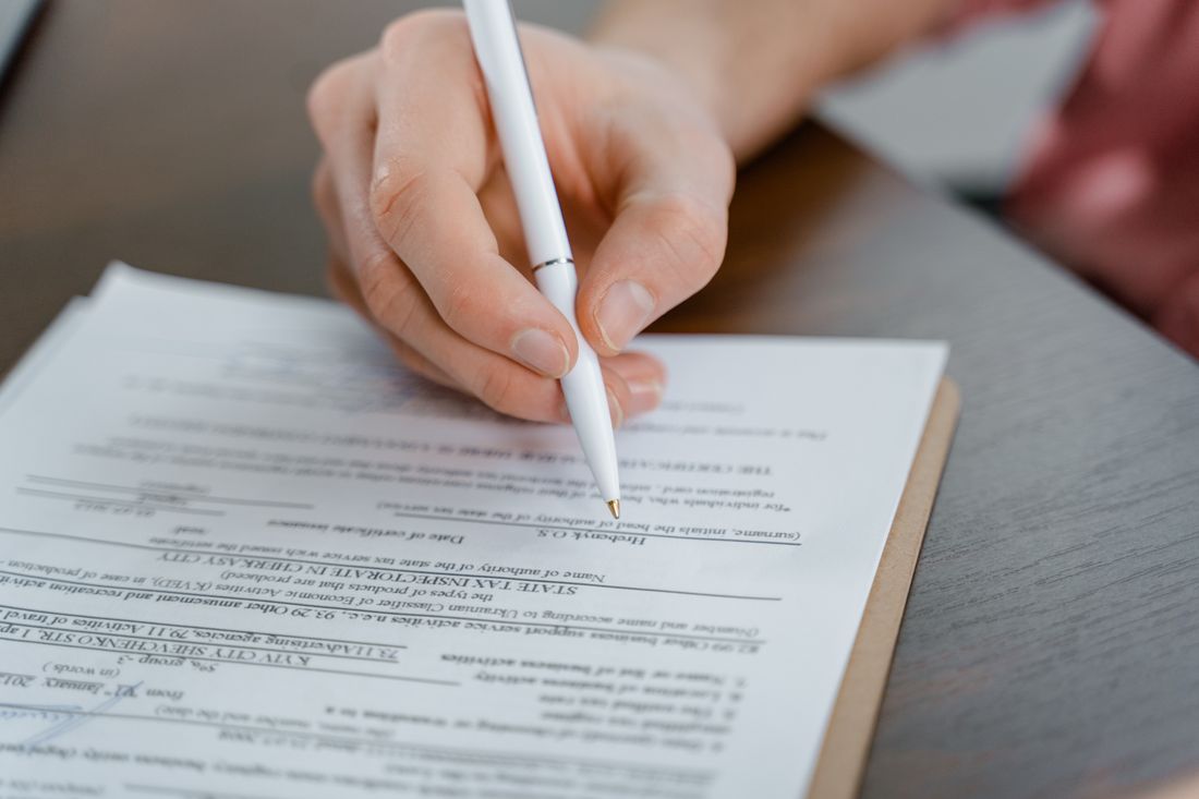 A hand signing a document