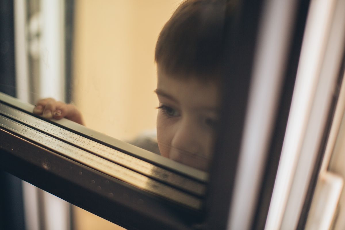 A child looks out a window, waiting